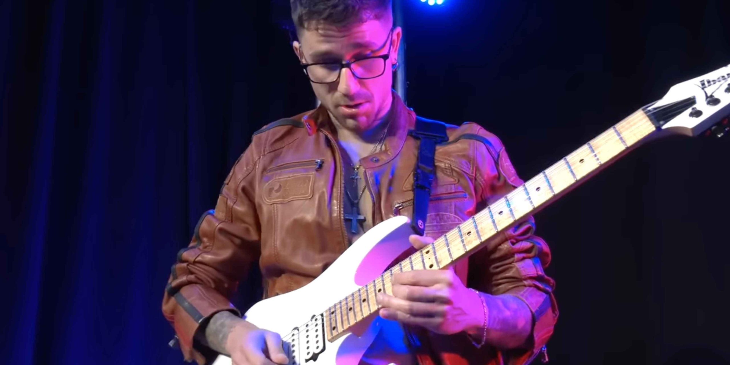 Davide Lo Surdo performing live on stage with electric guitar, spotlight highlighting his intense guitar technique.