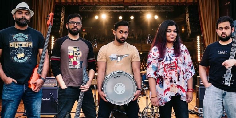 Full lineup of the band Opartheeb posing with instruments, including electric upright bass, snare drum, and electric guitars, against a wooden fence background.