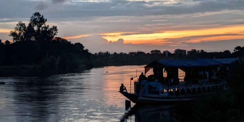 Neela Market Dhaka sunset silhouette of a traditional boat on the river near Purbachal 300 feet road.