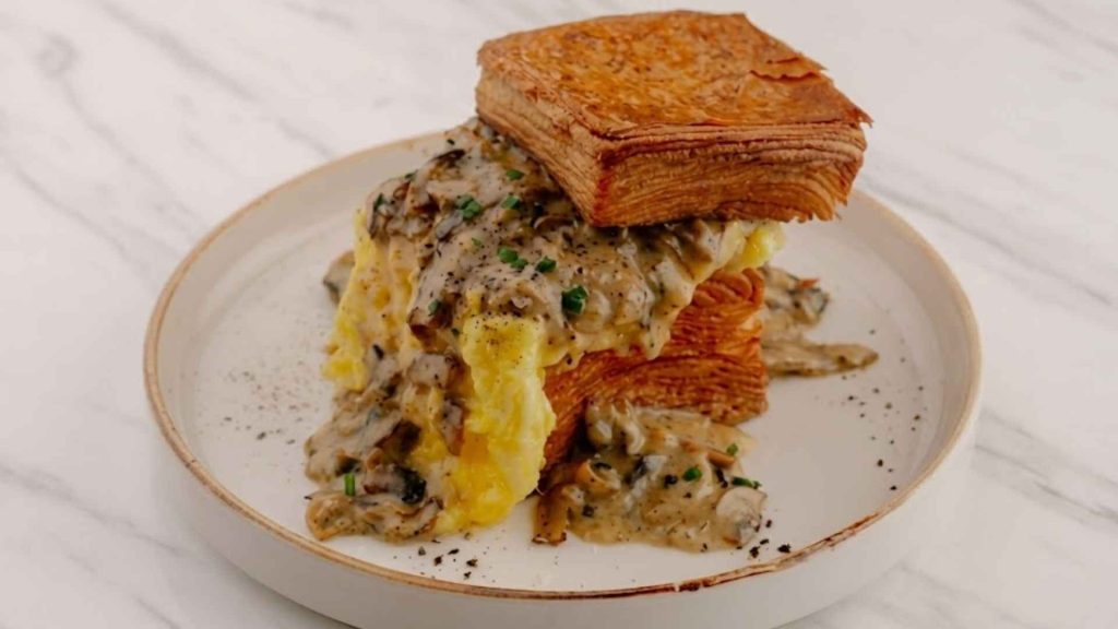 Slaw Bistro close-up of Chimichurri Eggs Benedict with poached eggs, avocado, and cilantro hollandaise.