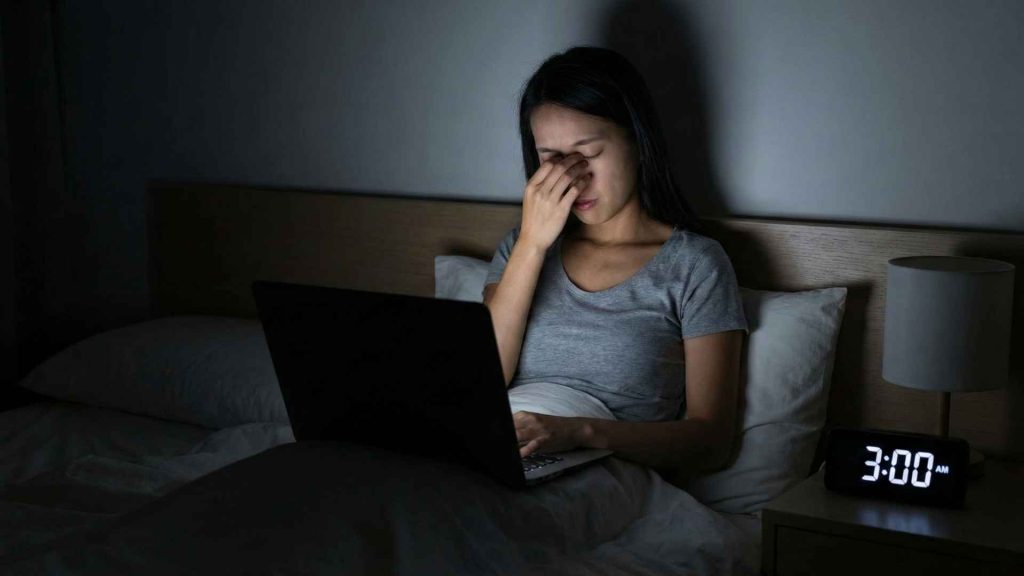 Stressed woman working on laptop at 3 AM
