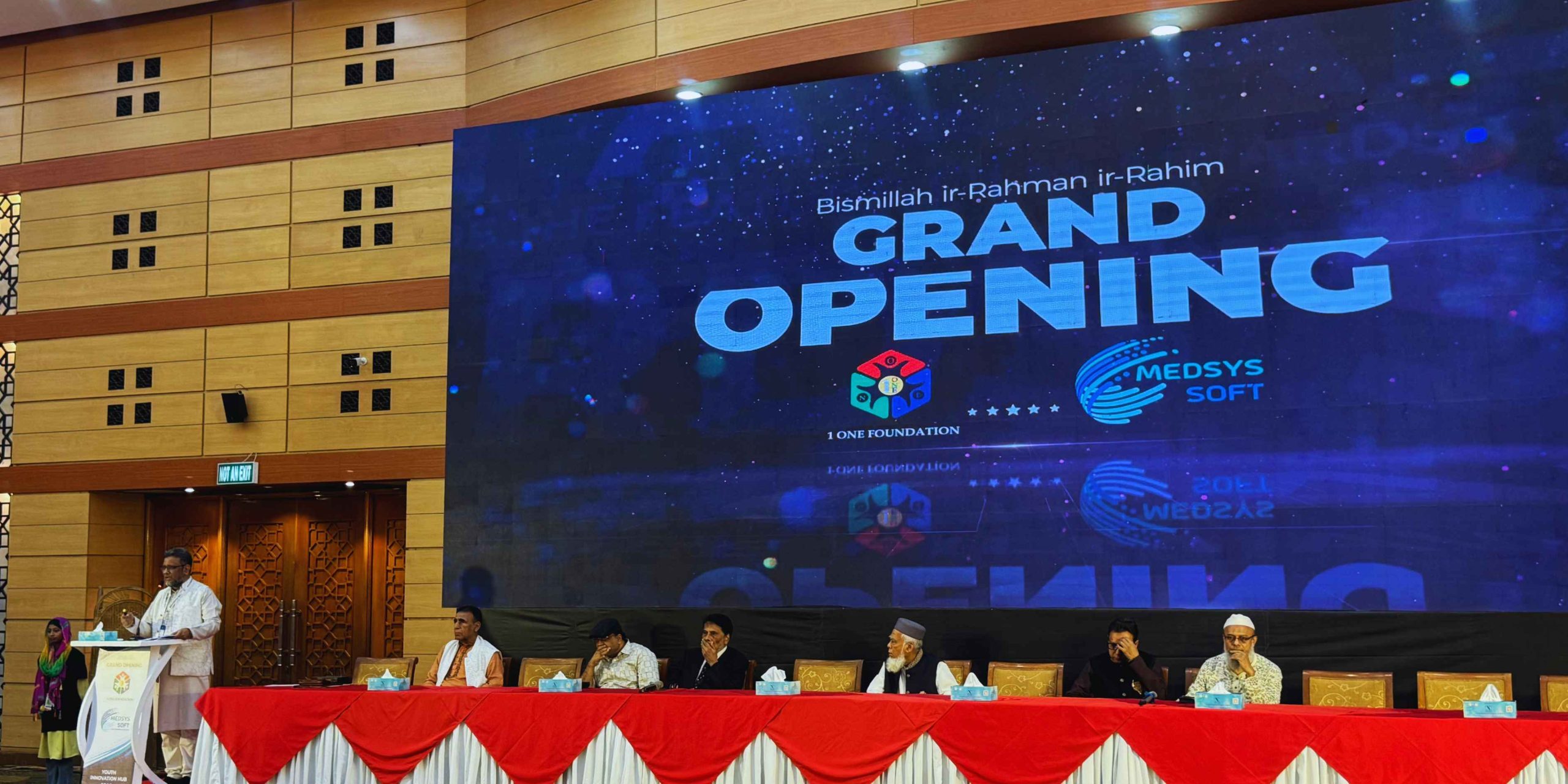 Main stage of 1One Foundation Grand Opening 2026 at BCFCC Dhaka featuring seated dignitaries and a large LED screen displaying "Grand Opening" and "Medsys Soft".