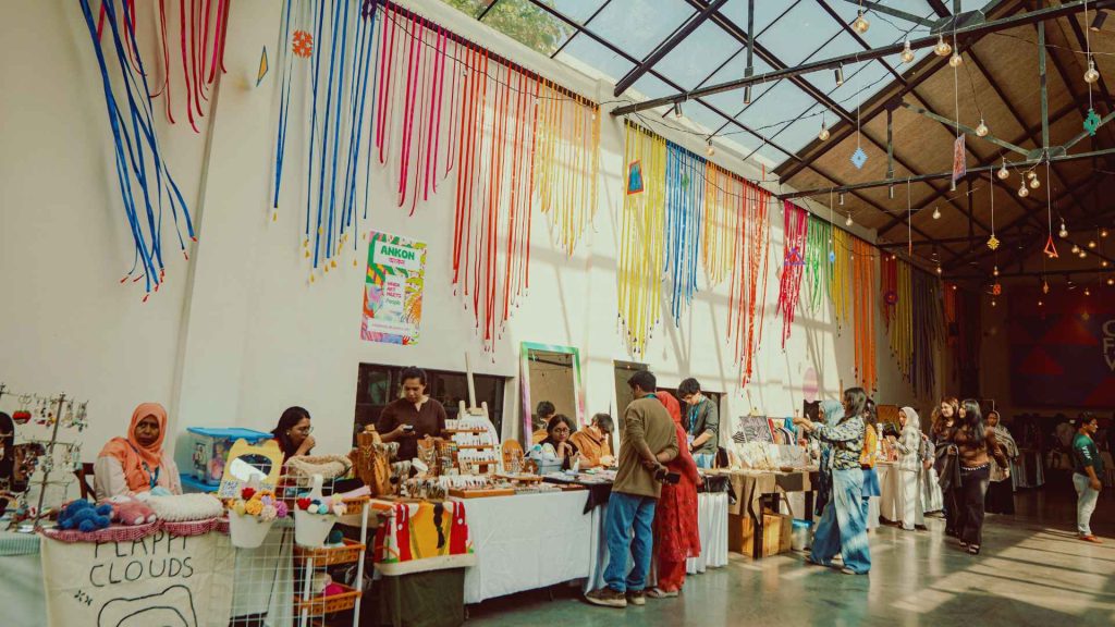 Festive indoor artisanal market and colorful streamers at the Arka Boishakh 1433 cultural event in Dhaka, Bangladesh.