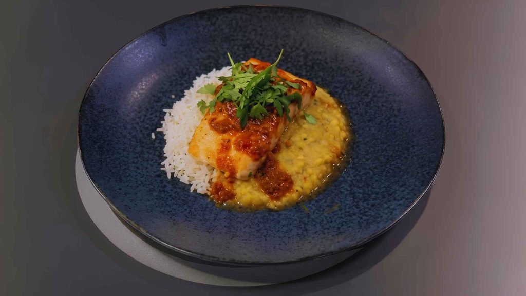A beautifully plated signature dish of seared salmon over dal and basmati rice, created by Shompa Kabir MasterChef.