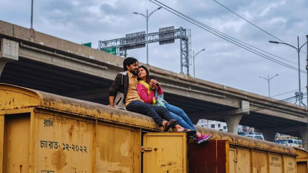 A romantic couple sitting on top of a yellow train car during a scene from the cinematic project Pressure Cooker.