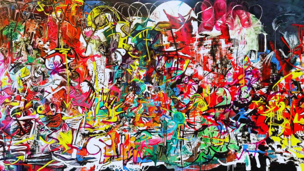 Mubtasim Alvee A Shared Condition — Contemporary artist Mubtasim Alvee sitting on a massive, colorful abstract floor painting in his creative studio space.
