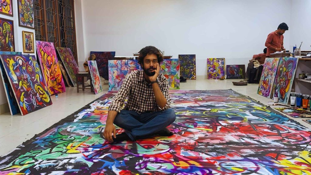 Mubtasim Alvee A Shared Condition — A wide-angle view of an art studio filled with large-scale abstract paintings and vibrant canvases leaning against white walls.